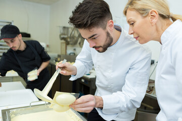 chocolatier apprentice pouring melted chocolate into egg mould