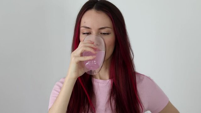 Beautiful young woman drinks electrolytes. The girl drinks rose water in a glass with electrolytes and vitamins. Detox water