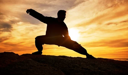 Gordijnen Man, meditation and silhouette, training and tai chi outdoor at a beach, wellness and calm with sunset background. Male, dark and shadow with martial arts, workout and meditate for a balance mindset © Beaunitta V W/peopleimages.com