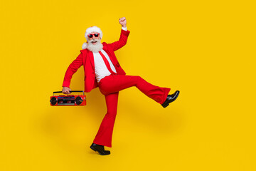 Fototapeta na wymiar Full length photo of funky cool santa dressed red suit tie enjoying boom box songs walking empty space isolated yellow color background