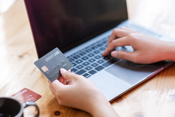 Close-up shot of hand holding credit card and using laptop Businesswoman or entrepreneur working from home online shopping, ecommerce, internet banking, take money, work from home concepts
