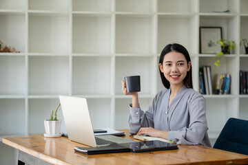 Asian businesswoman working with laptop computer Calculate, analyze, young woman, financial advisor, prepare statistical report, study documents, check financial charts in the office.