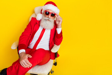 Portrait of successful serious aged man sitting chair empty space isolated on yellow color background