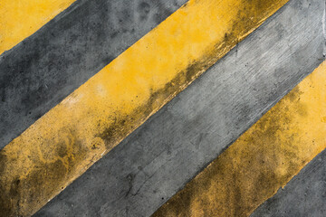 Yellow caution warning stripes lines on rough concrete wall grunge texture background with...
