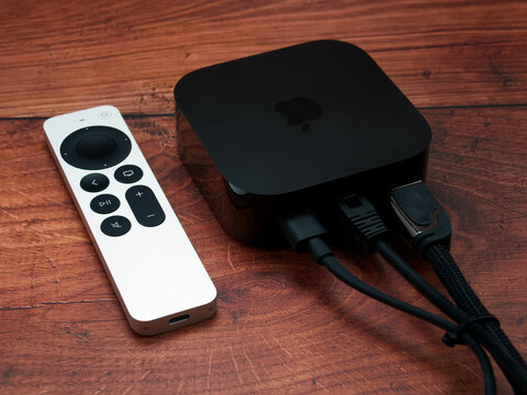 Bucharest, Romania - December 4, 2022: Product shot of the Apple TV 4k 2022 with WiFi and Ethernet, 128Gb RAM, and with Siri Remote, on oak wood background, back view with cables