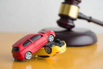 Car accident, auto insurance and judge gavel law concept. Red and yellow car model crash, wooden...