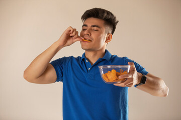Young man holding bowl and eating potato chips