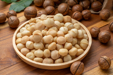 Roasted Macadamia nut in wooden plate on wooden background, Macadamia nuts on wooden background.