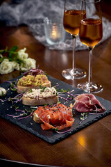 Assorted bruschetta with jamon, salmon and others. Italian appetizers on a black board. Close-up, selective focus