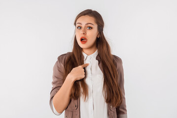 Beautiful shocked and surprised woman with open mouth pointing finger herself, stand over white studio background. Pretty brunette girl expresses great surprise