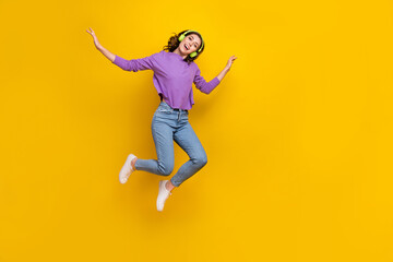 Naklejka na ściany i meble Full size portrait of cheerful delighted girl enjoy favorite music jumping isolated on yellow color background