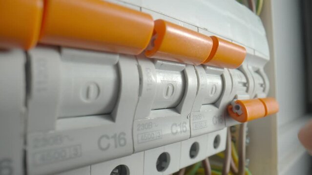 Finger turning on high voltage electrical switches in switchboard. Automatic fuses switch box. Close up, electric switch power supply. Switch on circuit breakers. Automatic breakers switching on.