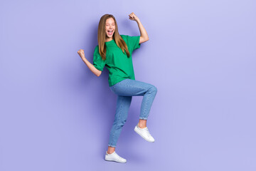 Fototapeta premium Full length photo of lucky funny girl dressed green t-shirt walking rising fists isolated purple color background