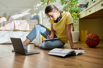 Teenage girl with glasses studying at home using a laptop