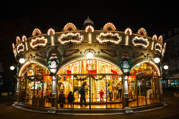 Fototapeta na wymiar COLMAR, FRANCE - December 2016 - Carousel with Christmas decorations red bows and illuminations