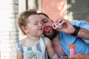 Dad and little daughter are blowing soap bubbles
