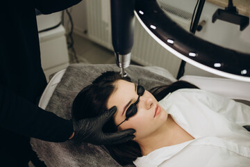 Laser removal of permanent make-up on face lips of young woman in salon. Concept Rejuvenation...