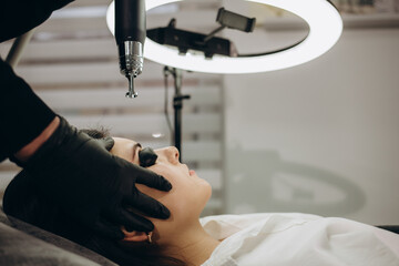 Laser removal of permanent makeup. The beautician removes the tattoo from the eyebrows.