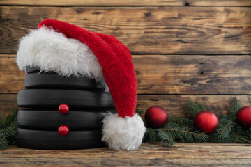 Dumbbells weight plates in red Santa Claus Christmas hat, stacked on top of each other in shape of...