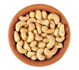 Cashew nuts in clay pot isolated on white, top view