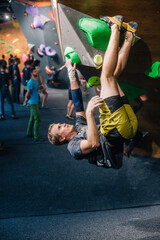 A young, athletic guy with a beautiful inflated body climbs a bouldering in a climbing hall. Emotions on the face.