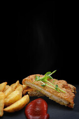 Schnitzel with potatoes, sauce and herbs. on a black background