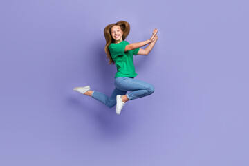 Fototapeta na wymiar Full length photo of excited shiny girl dressed green t-shirt smiling jumping high isolated purple color background