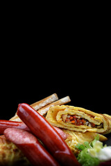 Omelet with vegetables, sausages and toast on a black background. Vertical