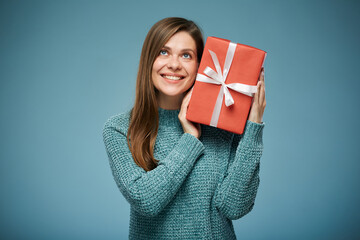 Woman in green sweater holding red gift near face and lookin up. Advertising female studio portrait.