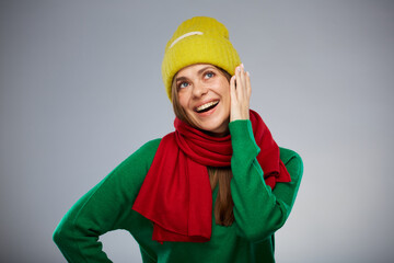 Happy surprising woman in casual warm clothes touching her face and looking up. Advertising female studio portrait.