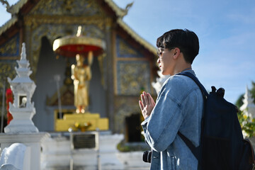 Young asian man traveler praying and worship buddha in the buddhist temple
