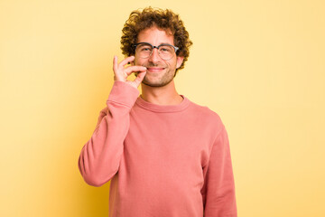 Young smart caucasian man on yellow background with fingers on lips keeping a secret.