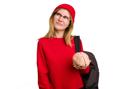Young caucasian student woman holding a brain isolated dreaming of achieving goals and purposes