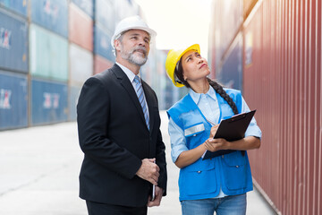 Male and female container yard workers discuss of container boxes from cargo freight ship at...