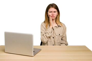 Young caucasian woman in a workplace working with a laptop isolated having a strong teeth pain,...