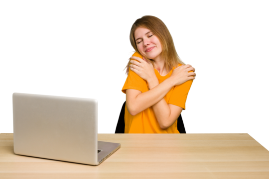 Young caucasian woman in a workplace working with a laptop isolated hugs, smiling carefree and happy.