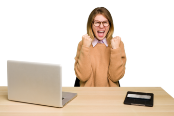 Young caucasian woman in a workplace working with a laptop isolated cheering carefree and excited. Victory concept.