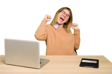 Young caucasian woman in a workplace working with a laptop isolated celebrating a special day, jumps and raise arms with energy.