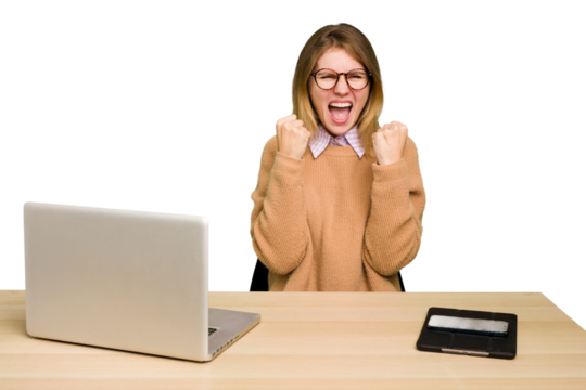 Young caucasian woman in a workplace working with a laptop isolated cheering carefree and excited. Victory concept.