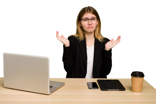 Young business caucasian woman working on her workplace cutout isolated doubting and shrugging shoulders in questioning gesture.