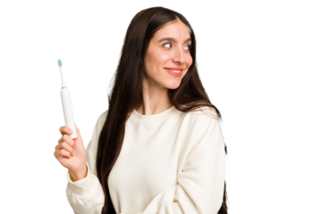 Young caucasian holding a brushing teeth isolated looks aside smiling, cheerful and pleasant.