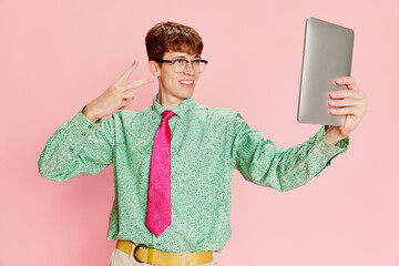 Funny emotional man, student geek wearing vintage style shirt and trousers having fun, using tablet...
