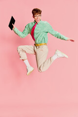 Funny emotional man, student geek wearing vintage style shirt and trousers having fun, using tablet...