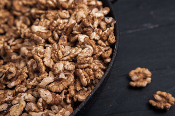 Walnut background. Peeled walnuts on a iron plate on black. walnuts a real super food full of vitamins and vegetable fats