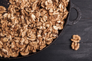 Walnut background. Peeled walnuts on a iron plate on black. walnuts a real super food full of vitamins and vegetable fats