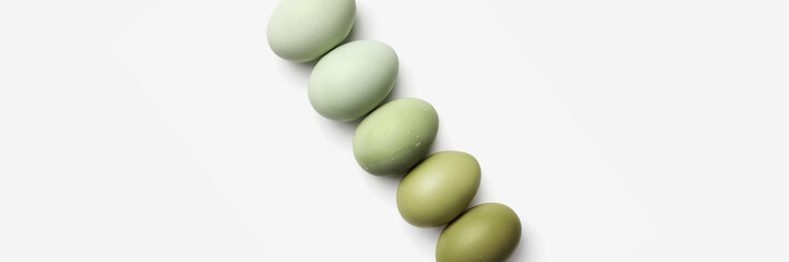 Top view of five boiled chicken eggs in row. Minimal style photo made of natural colors eggs on white background. Color gradient olive tones. Healthy protein food Wide banner, copy space