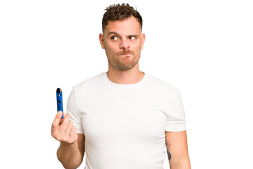 Young caucasian man holding a electronic cigarette isolated confused, feels doubtful and unsure.