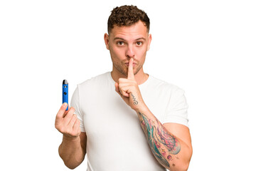 Young caucasian man holding a electronic cigarette isolated keeping a secret or asking for silence.