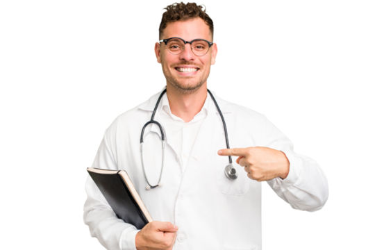 Young doctor caucasian man holding a book isolated person pointing by hand to a shirt copy space, proud and confident