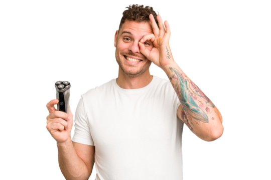 Young caucasian man holding a razor isolated excited keeping ok gesture on eye.
